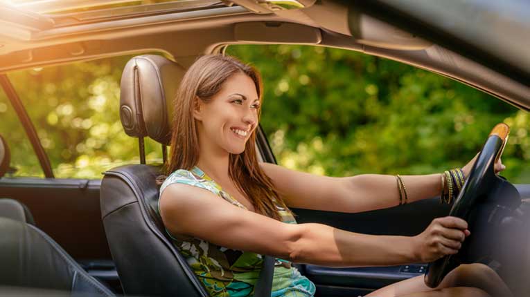 A pre-approved car loan helps you leave your memorial day car sales happy like this woman driving her new car.